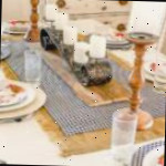 Uma mesa decorada com pratos de comida sobre um prato, decorada com caminho de mesa e toalha