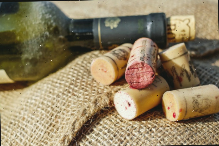 Garrafa de vinho e rolhas de vinho sobre juta.