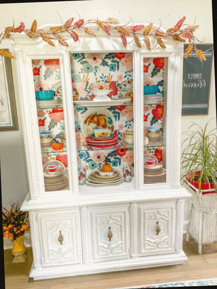 Aparador branco com papel de parede floral e decoração de outono no interior