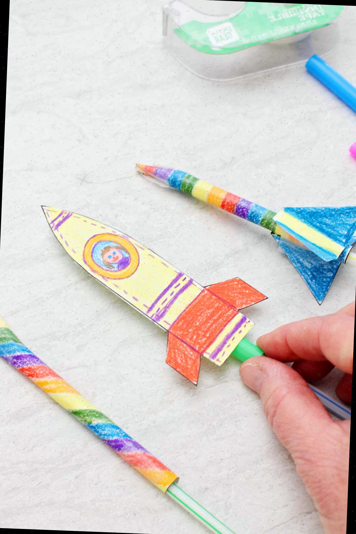 Três foguetes de canudo coloridamente pintados.