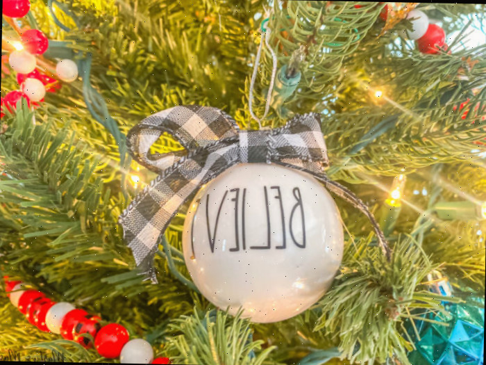 Ornamento branco com a palavra believe na árvore de Natal