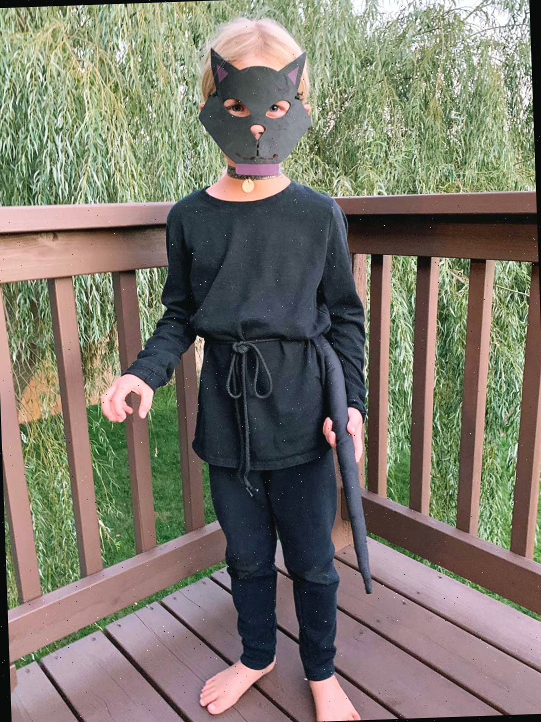 Uma jovem com cabelo loiro vestida como um gato preto em um deck.