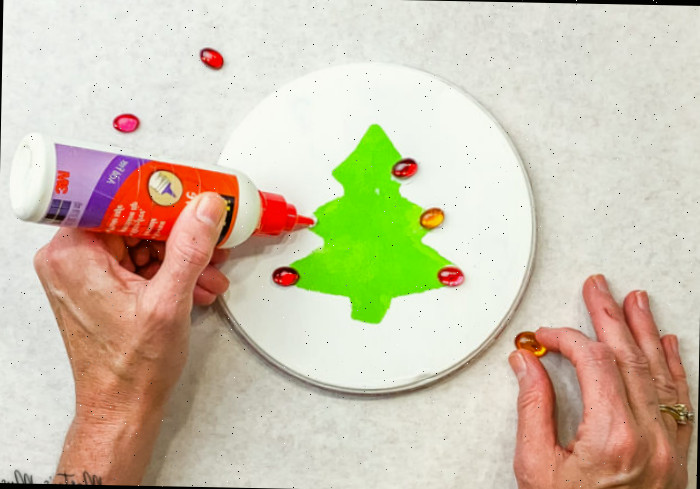 Adicionando pedras vermelhas à árvore de Natal estampada em verde