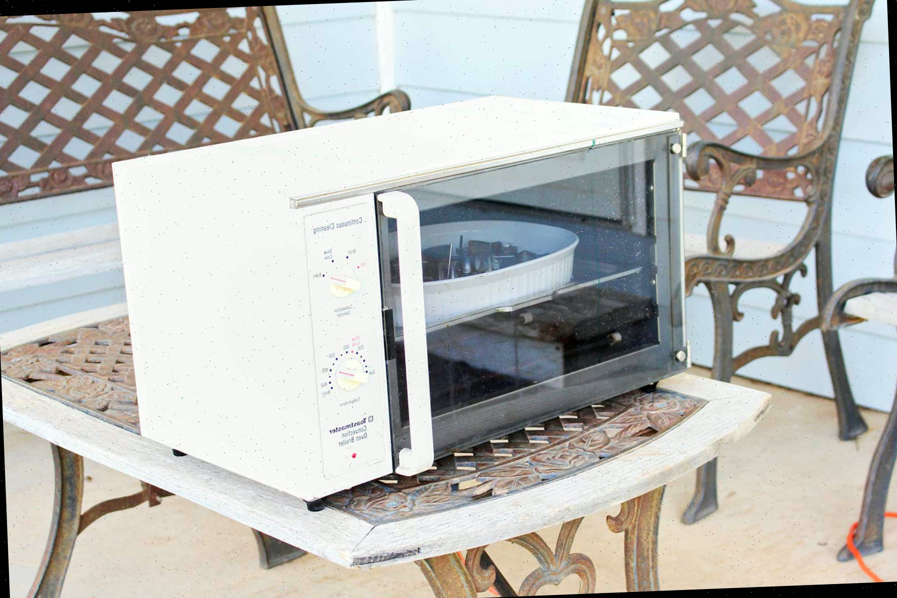 Um forno elétrico sobre uma mesa ao ar livre em uma varanda.