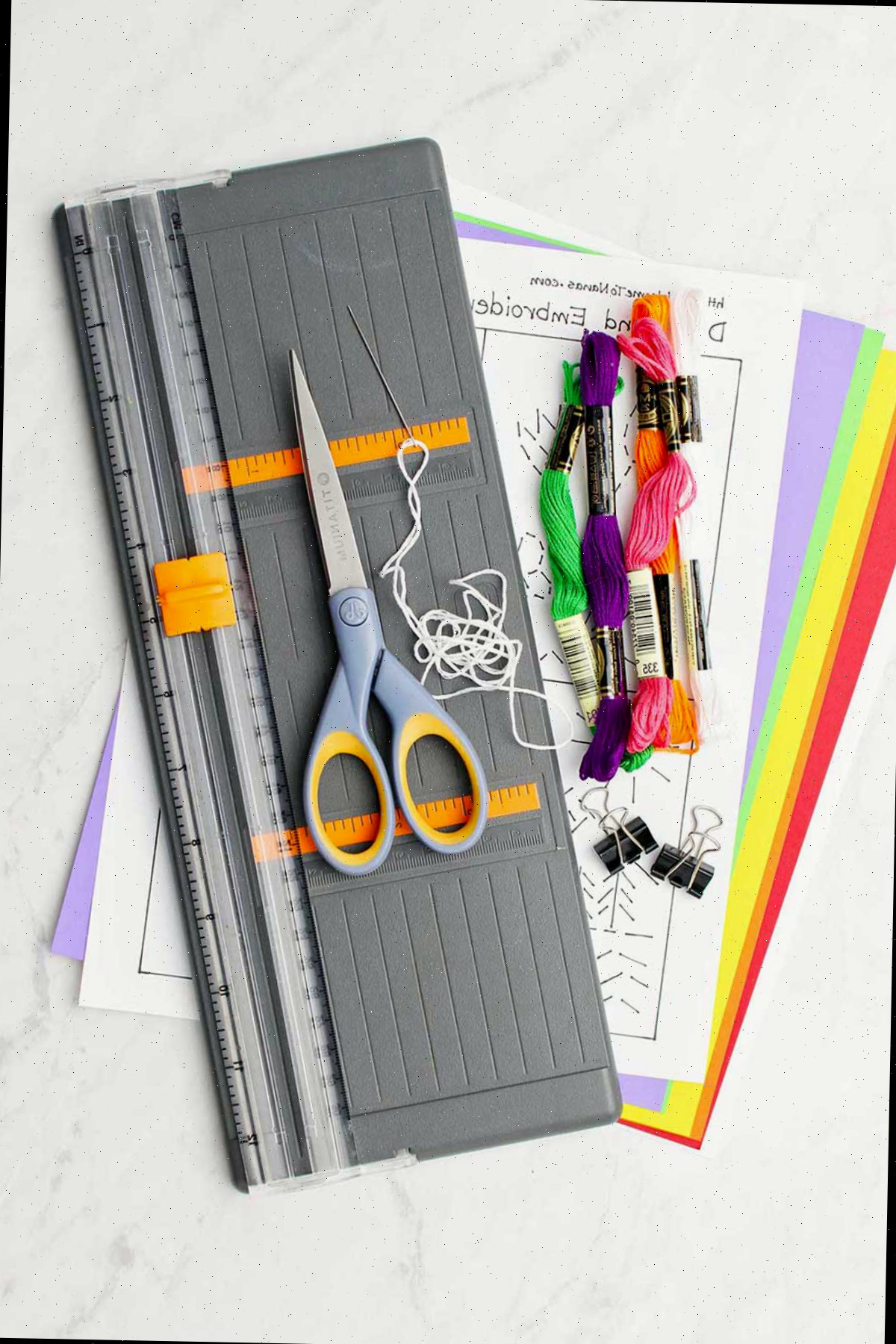 Materiais para cartão bordado à mão. Fios de bordado coloridos, papel, moldes, tesouras e cortador de papel.