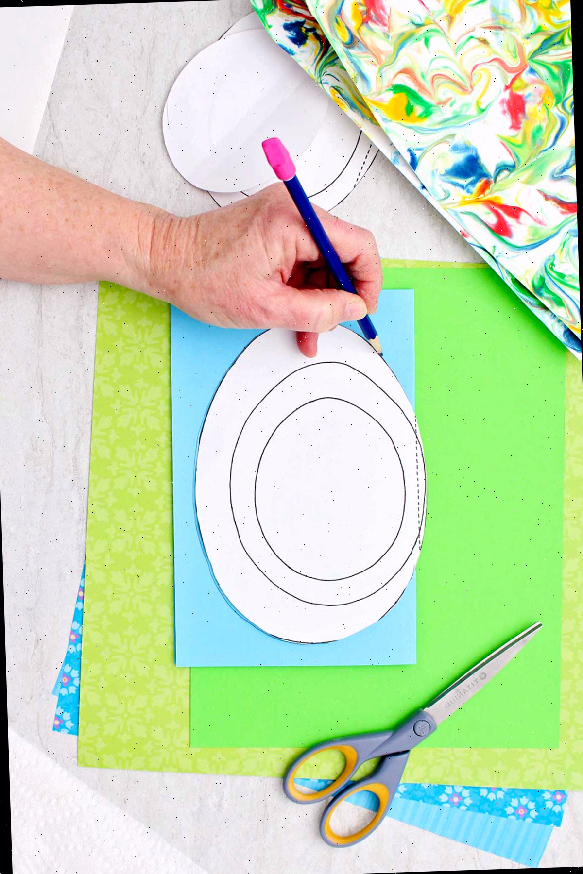 Indivíduo utilizando um molde em forma de ovo para traçar formas de ovo em papel azul.