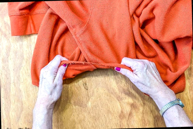 Rasgando um suéter laranja em tiras
