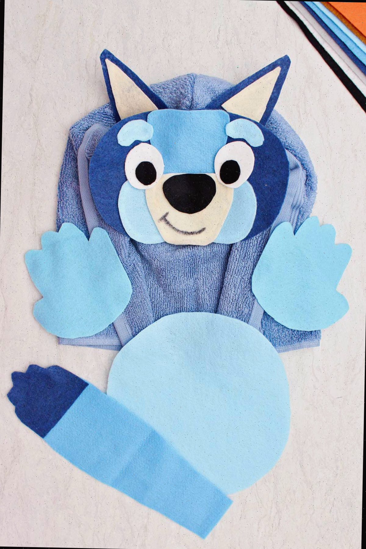 Uma fantasia de Halloween de blue healer feita de feltro e uma toalha de banho azul.