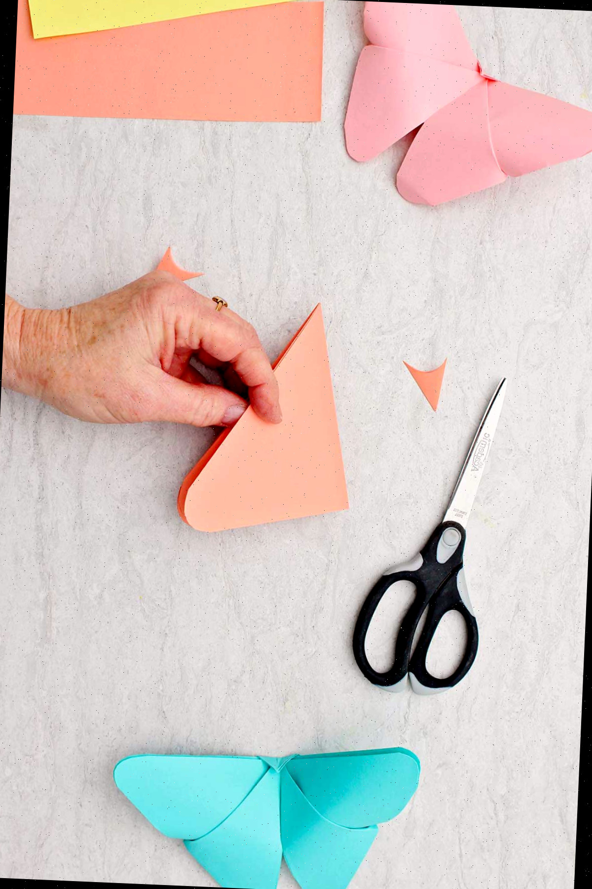 Uma pessoa segurando um pedaço de papel triângulo dobrado com bordas arredondadas.