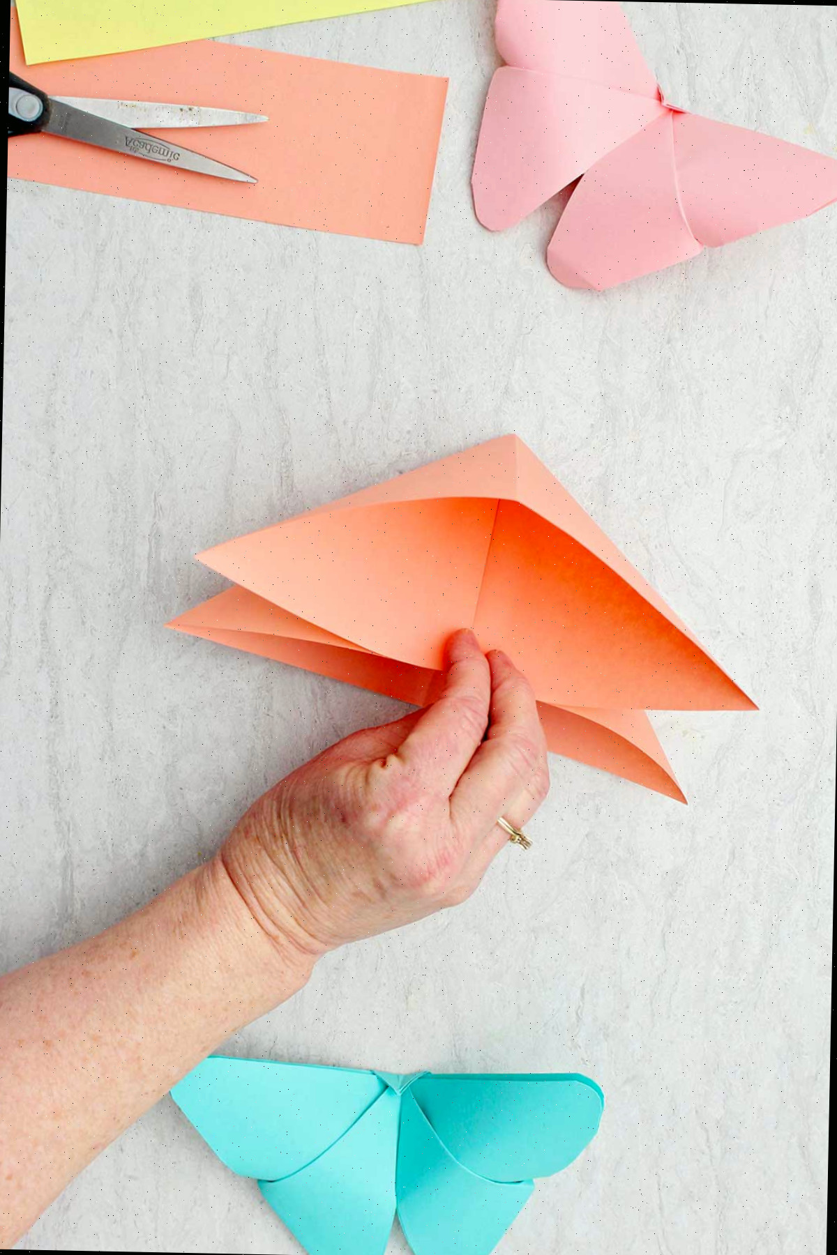 Uma pessoa mostrando a vista interna de uma folha de papel laranja dobrada.