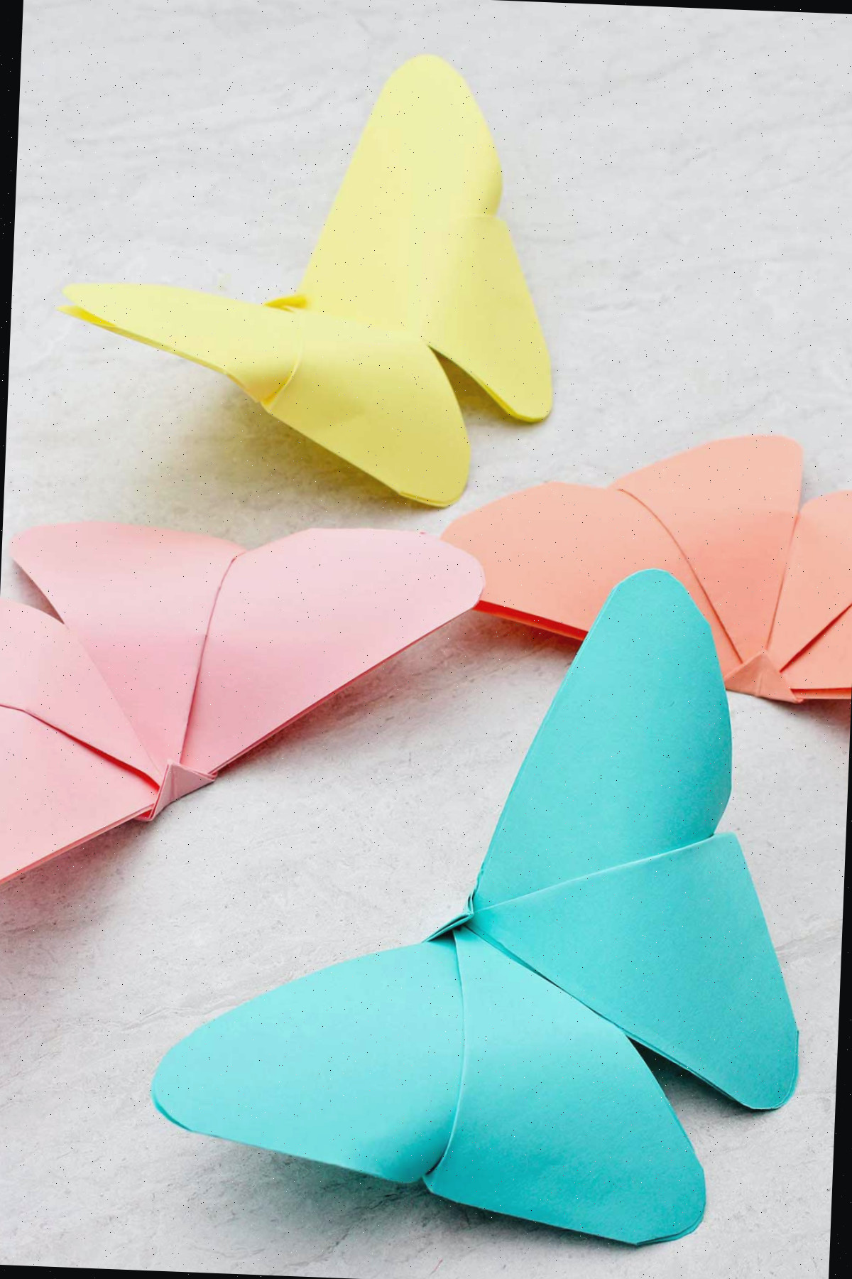 Quatro borboletas de origami em tons delicados de azul, amarelo, laranja e rosa.