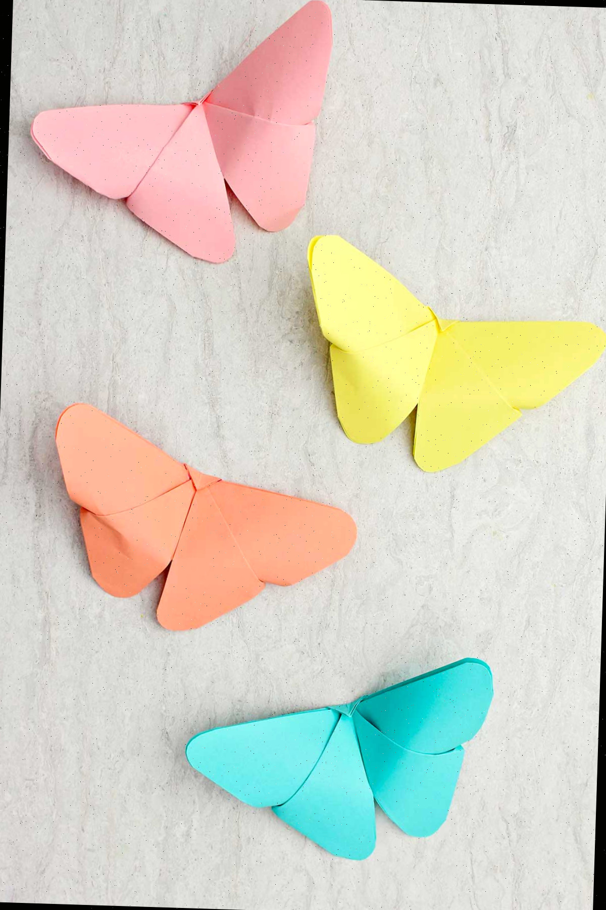 Quatro borboletas de origami em tons pastel de azul, amarelo, laranja e rosa.