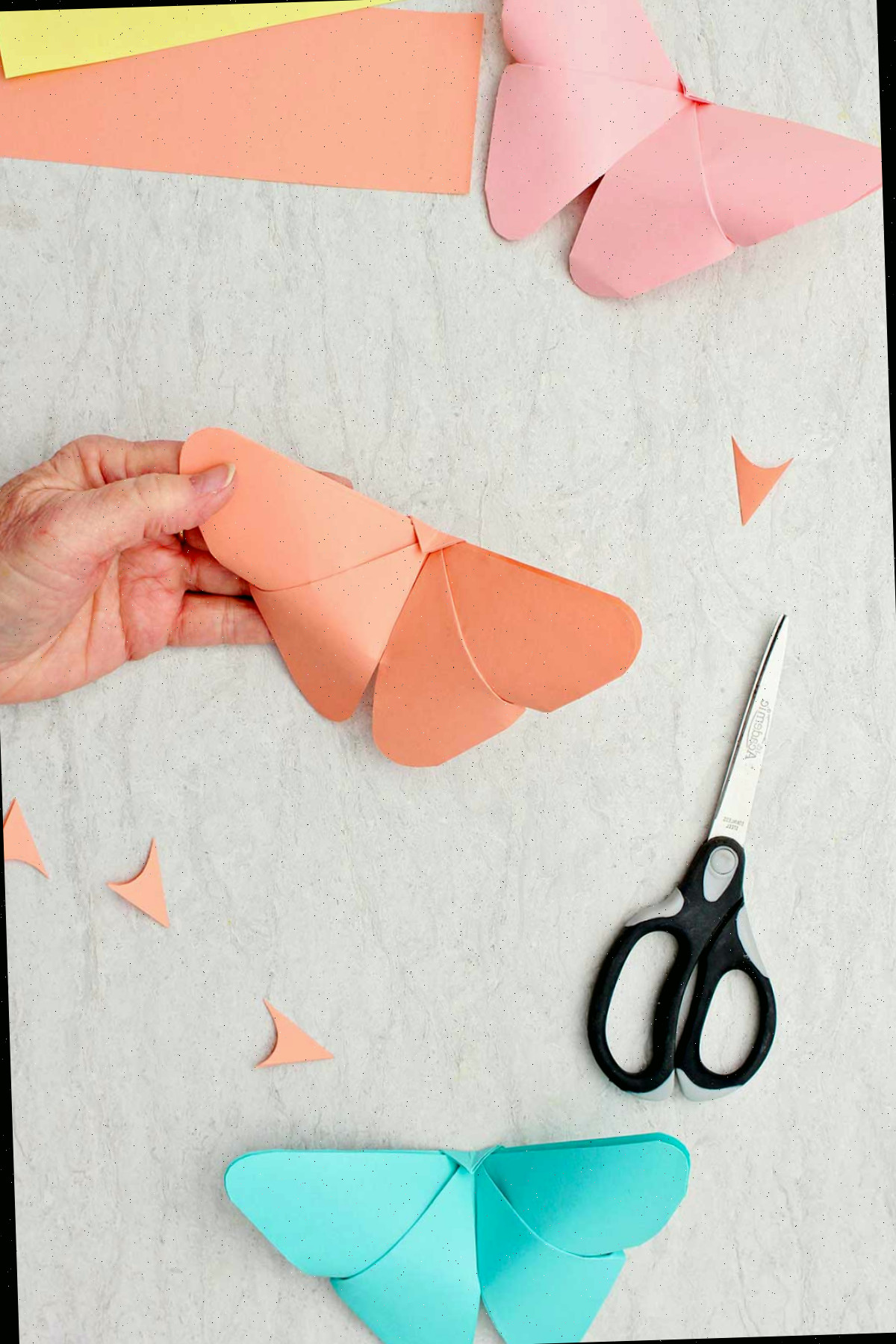 Uma borboleta de origami laranja finalizada com outras borboletas completas ao lado.