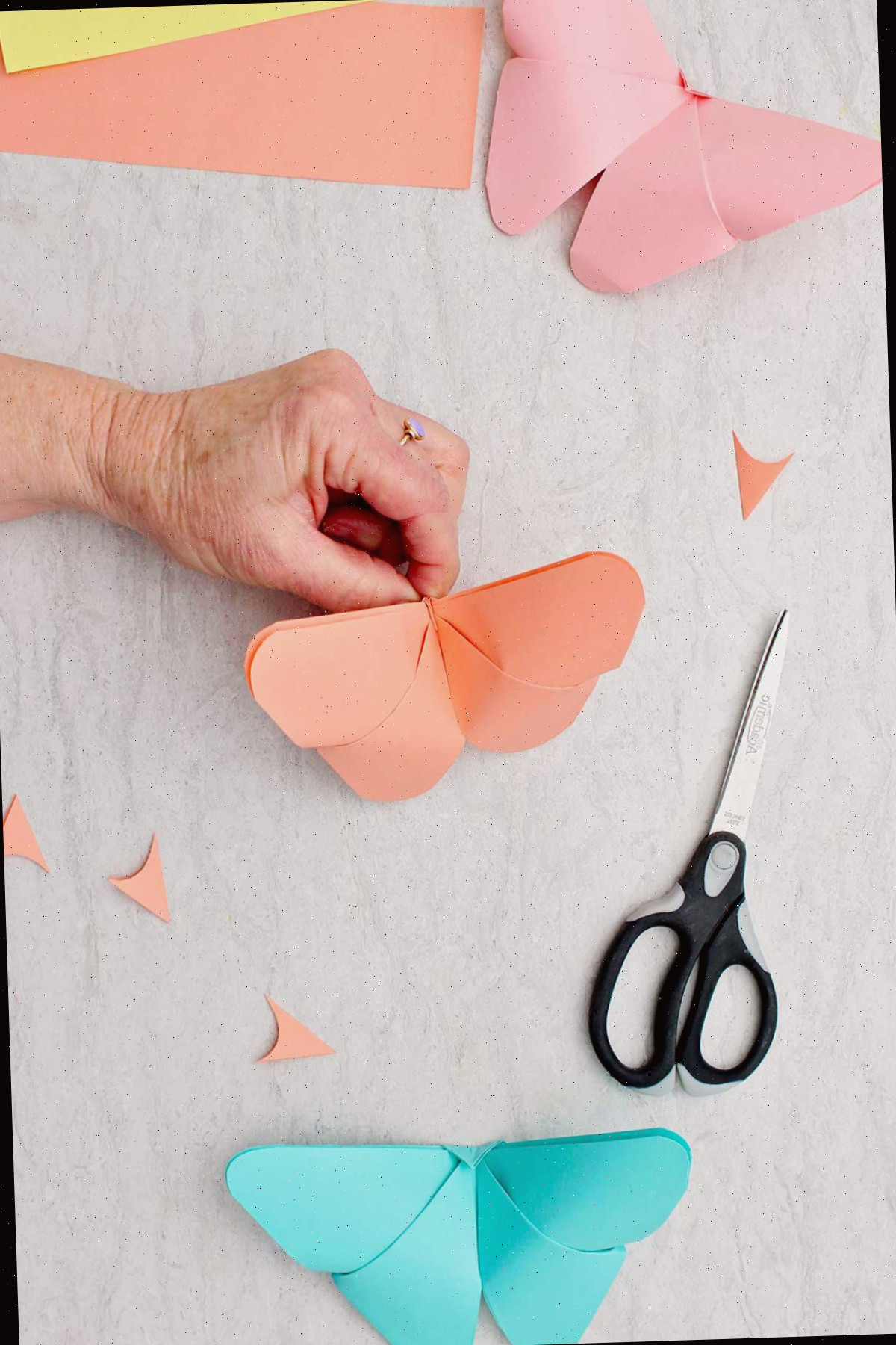 Uma borboleta de origami laranja finalizada com outras borboletas completadas próximas.