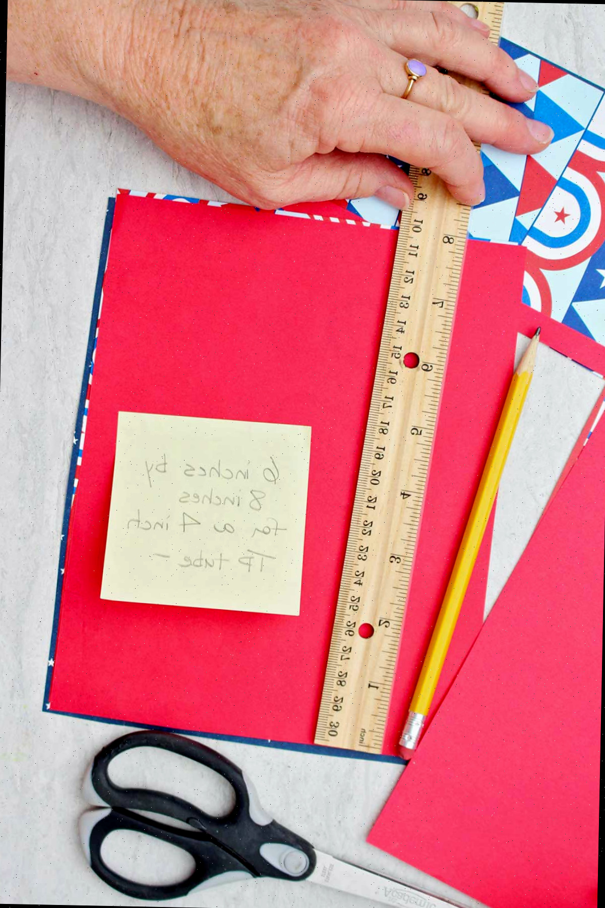 Pessoa medindo papel de scrapbooking para caber em volta de um tubo de papel toalha.