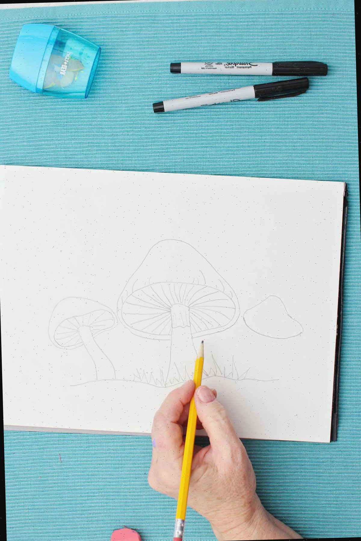 Um artista esboçando um desenho de um cogumelo com um lápis
