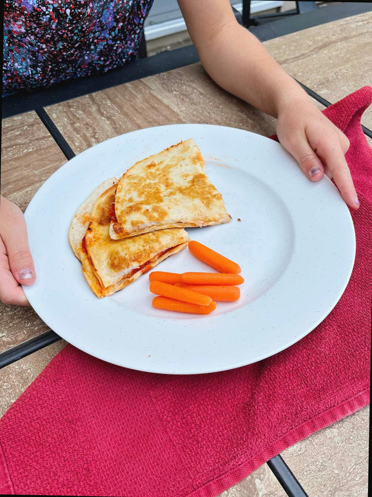 Duas quesadillas de pizza e cenouras baby em um prato branco.