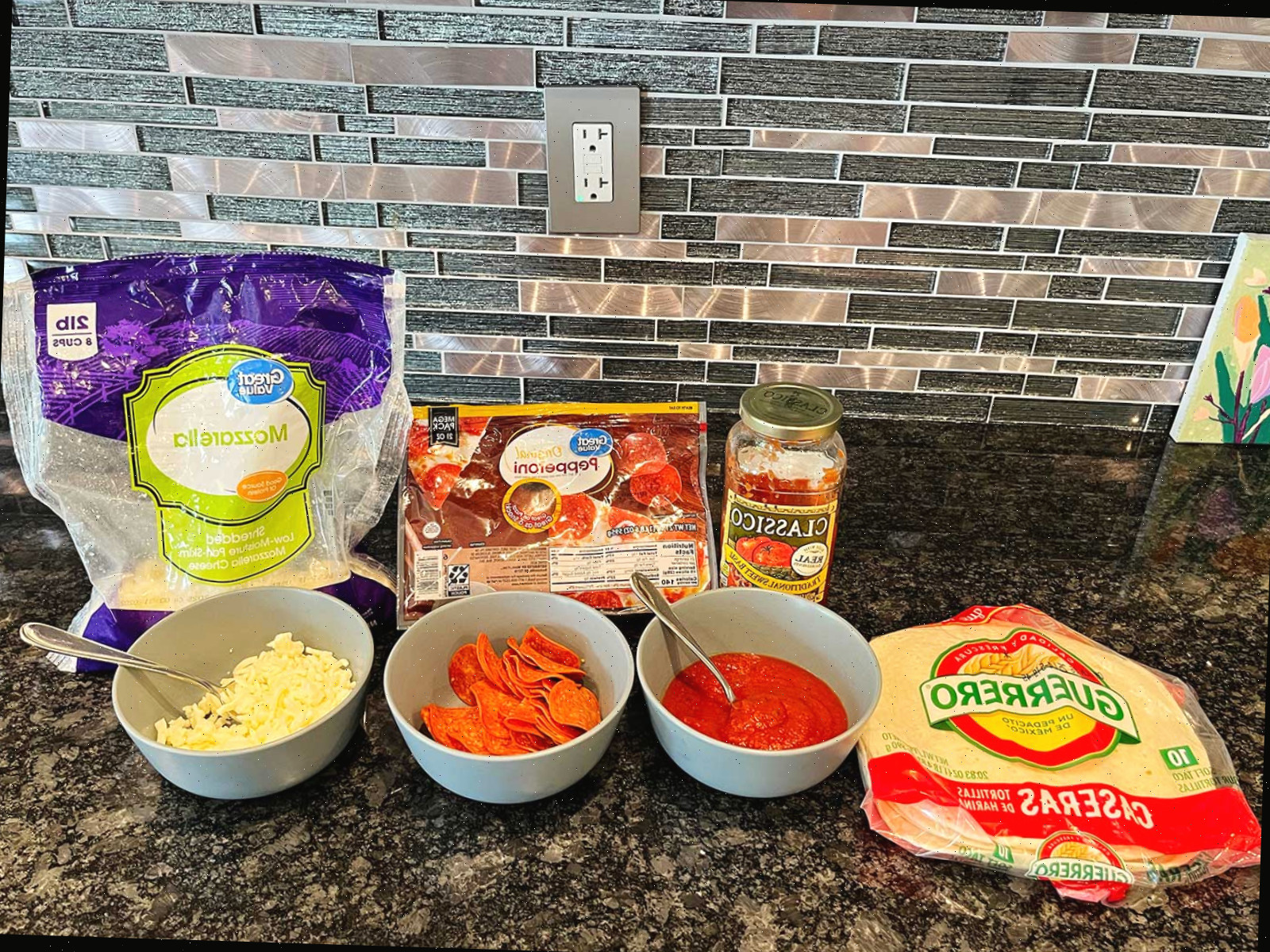 Materiais para preparar uma quesadilla de pizza em um balcão de mármore escuro.
