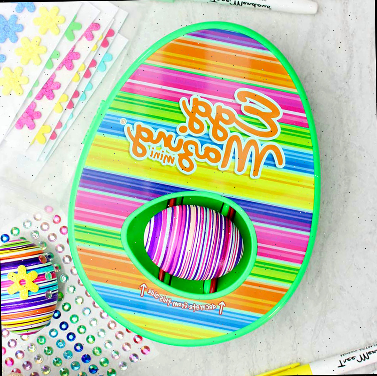 Kit de design listrado do EggMazing com ovo listrado colorido dentro e outros materiais próximos.