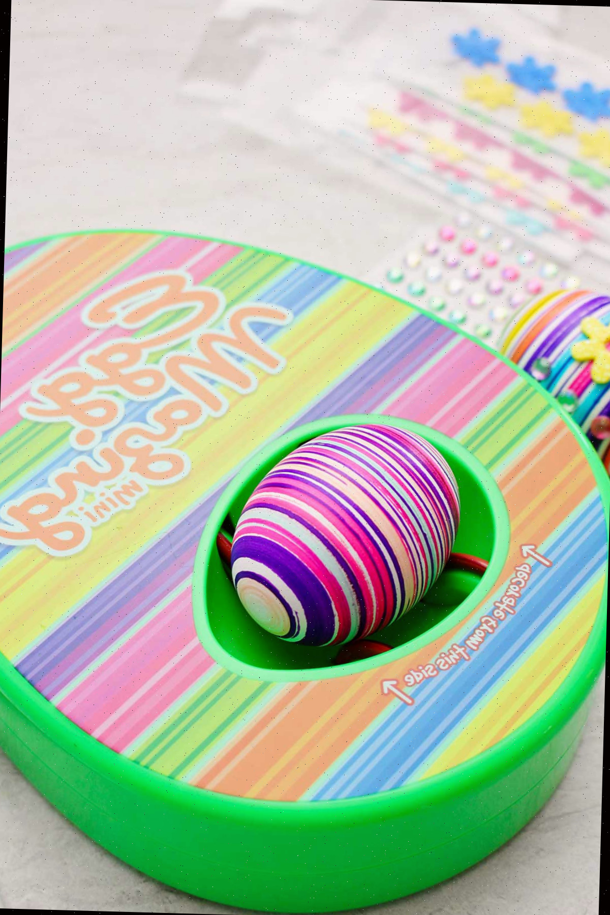 Kit de design com listras do EggMazing com ovo colorido listrado dentro e outros materiais por perto.