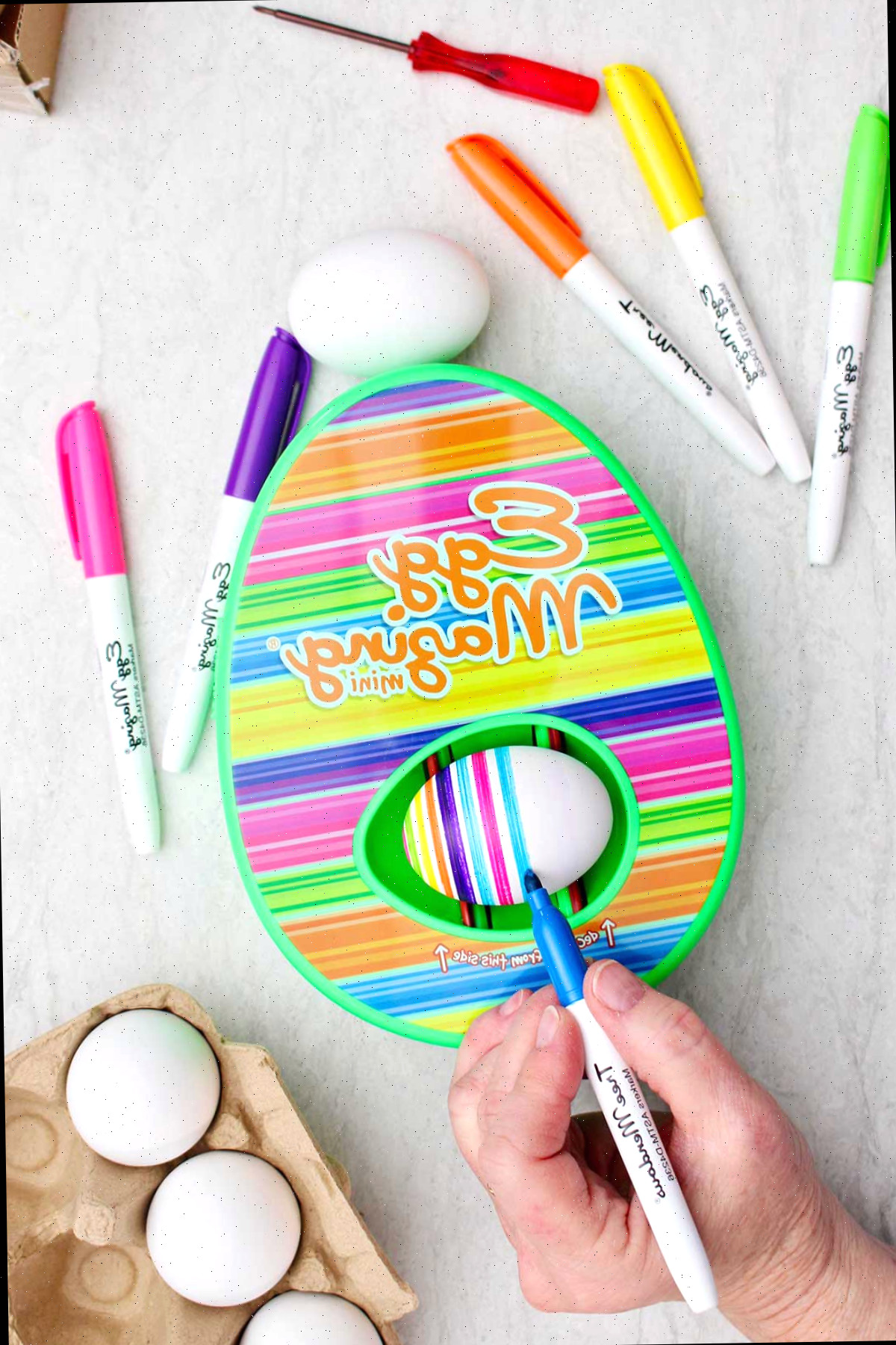 Uma pessoa utilizando um marcador azul para criar listras no ovo do kit EggMazing.