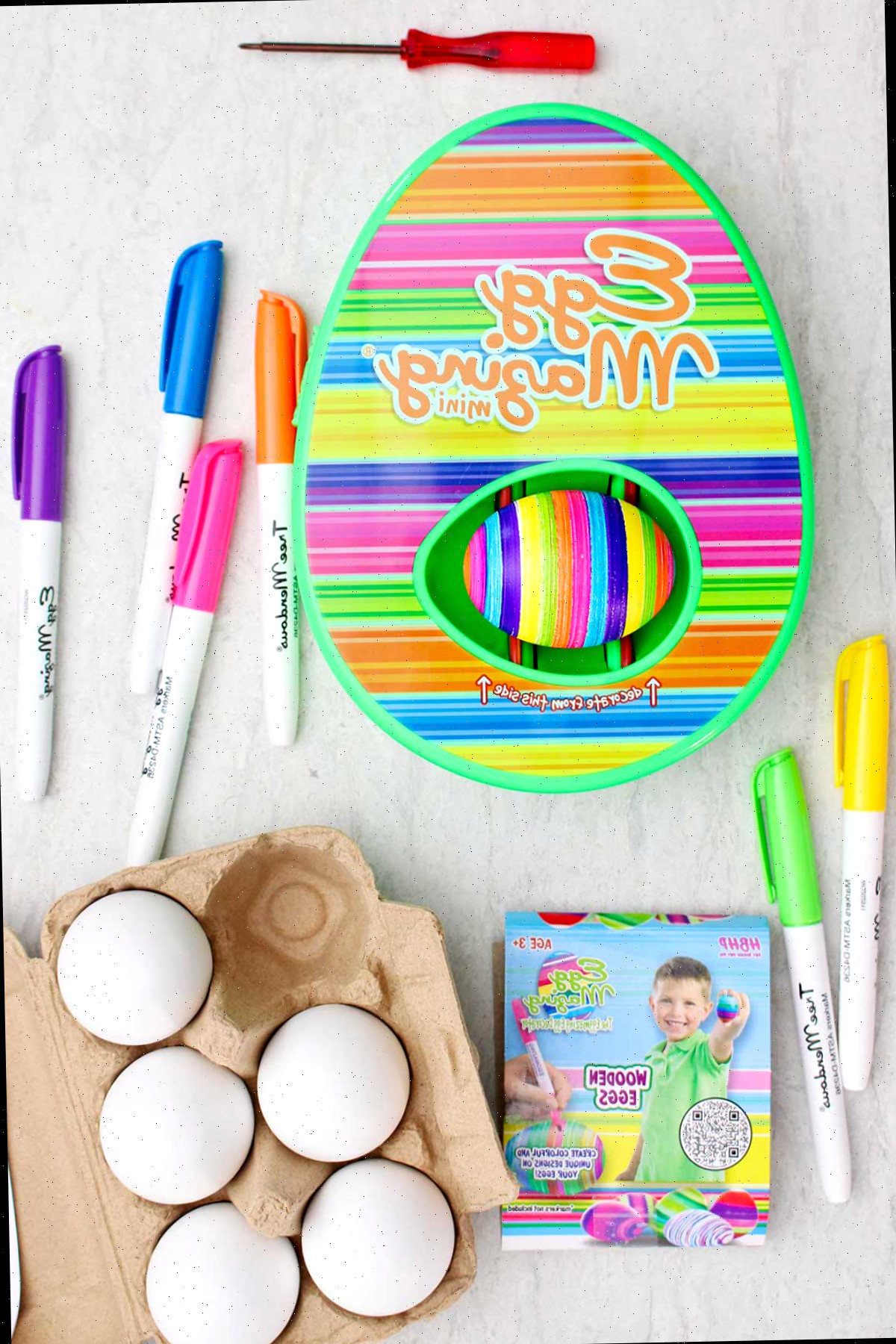 O kit listrado EggMazing completo com marcadores, ovos de madeira e ovos em uma cartela.