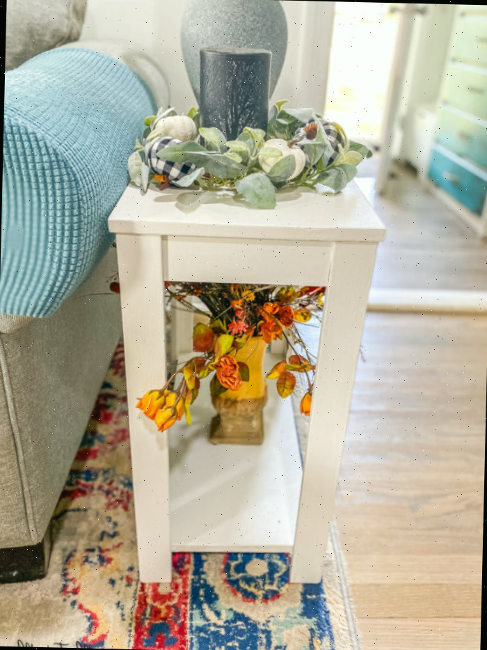 Pequena mesa branca com flores de seda sobre ela
