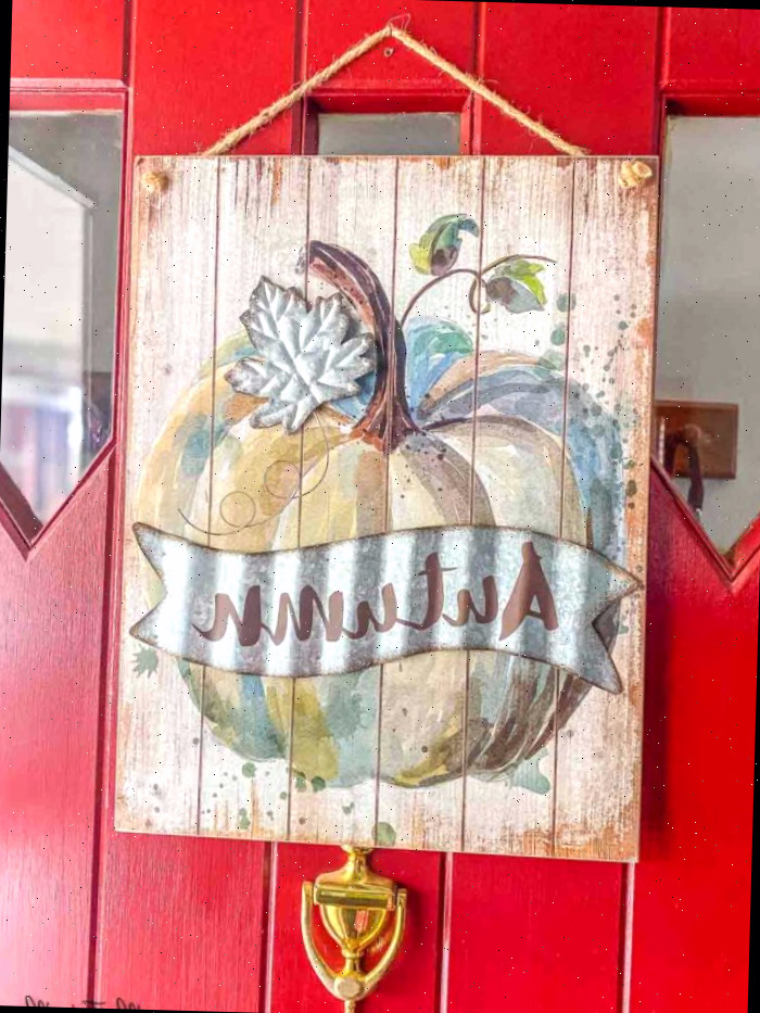 Imagem de outono pendurada na porta vermelha da entrada