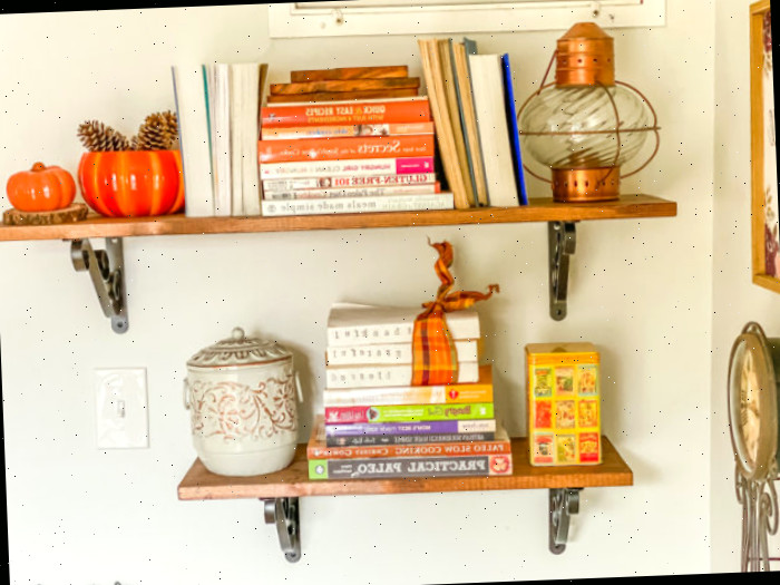 Prateleiras de madeira com livros de receita e decorações de outono