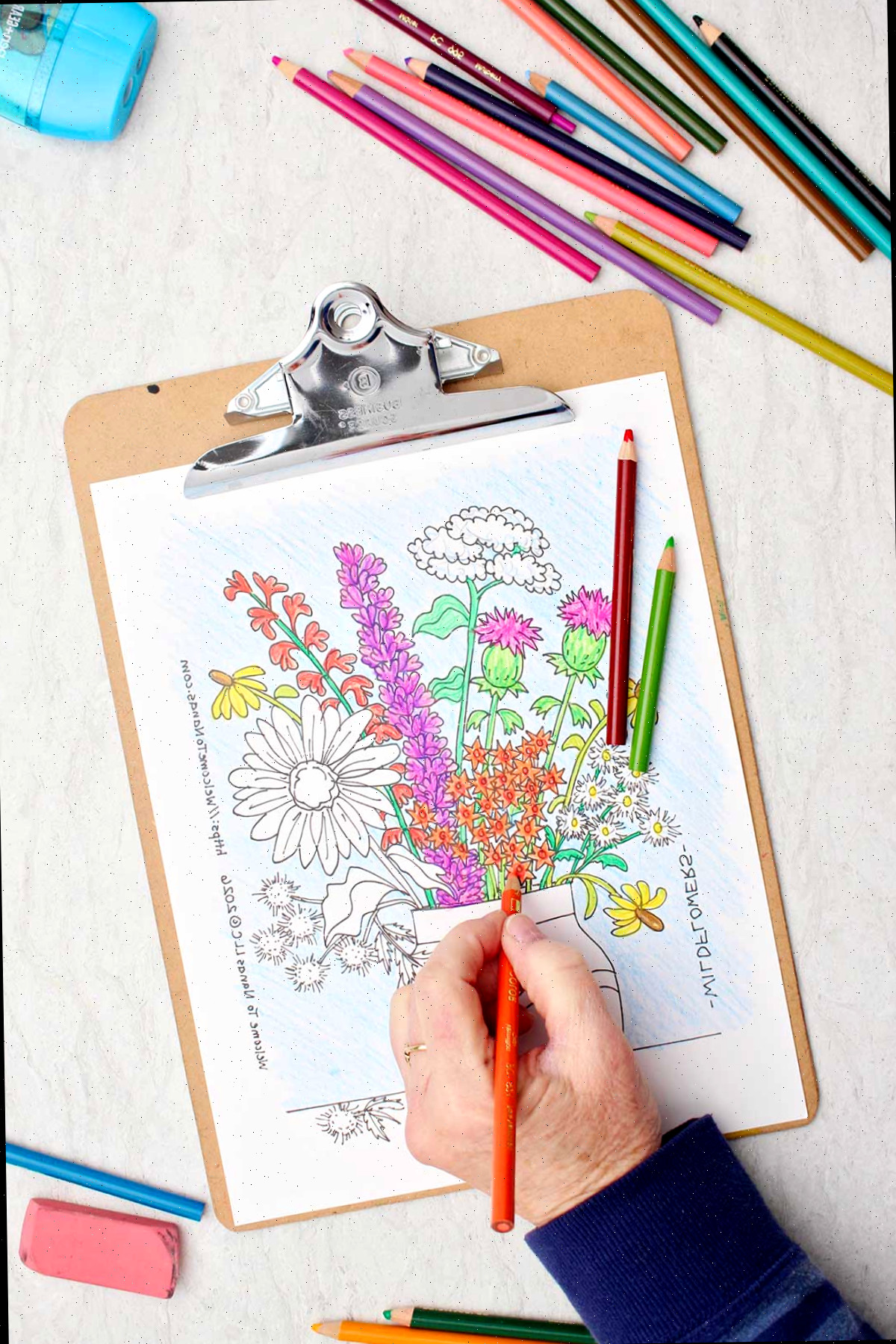Pessoa colorindo flores pequenas de laranja na página de colorir de um buquê de flores silvestres em um vaso.
