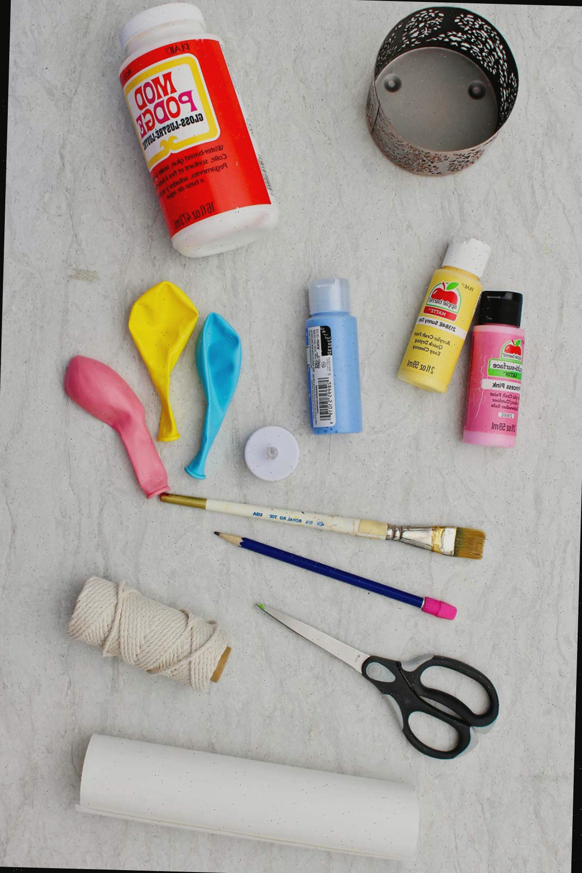 Materiais necessários para criar um mini balão de ar quente. Modge lodge, corda, balões, pincel, toalhas de papel, tinta, tesoura e uma cesta de metal.