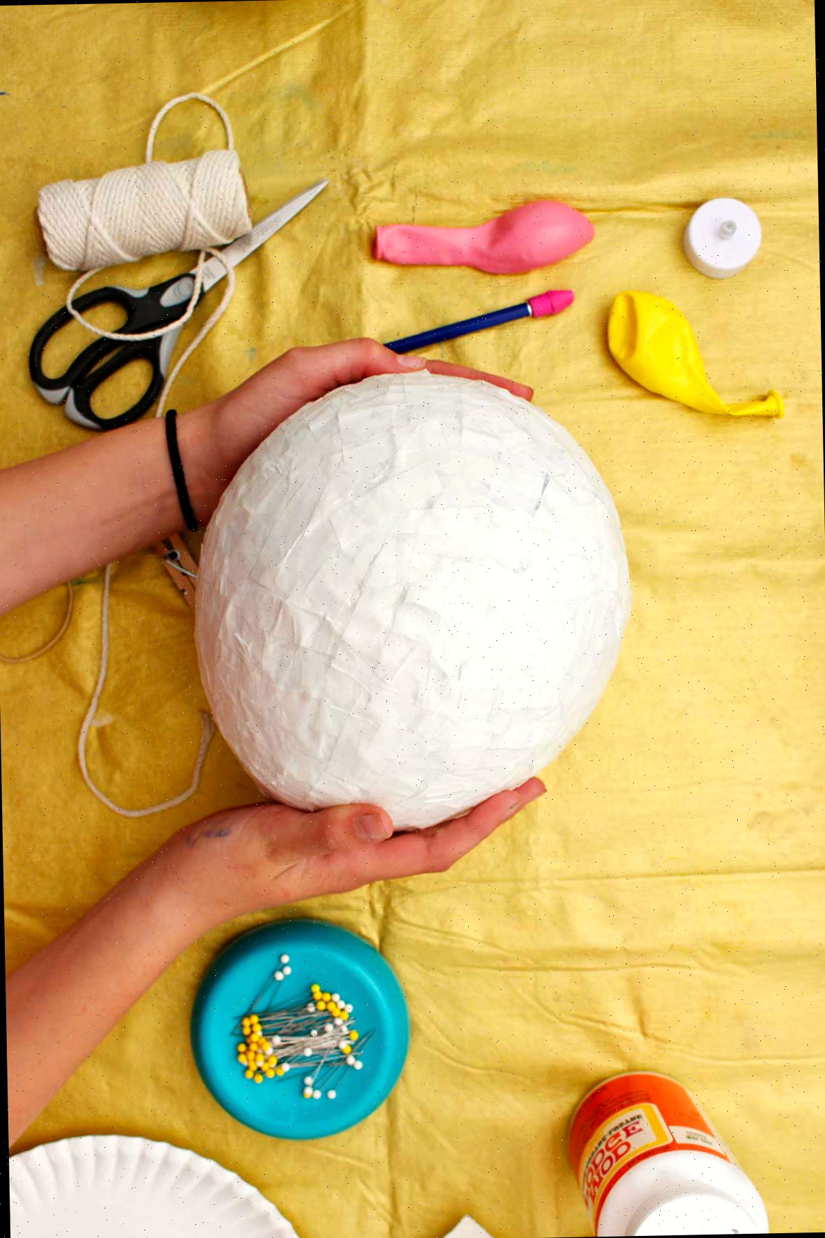 Indivíduo segurando um balão de papel machê seco antes de pintar.