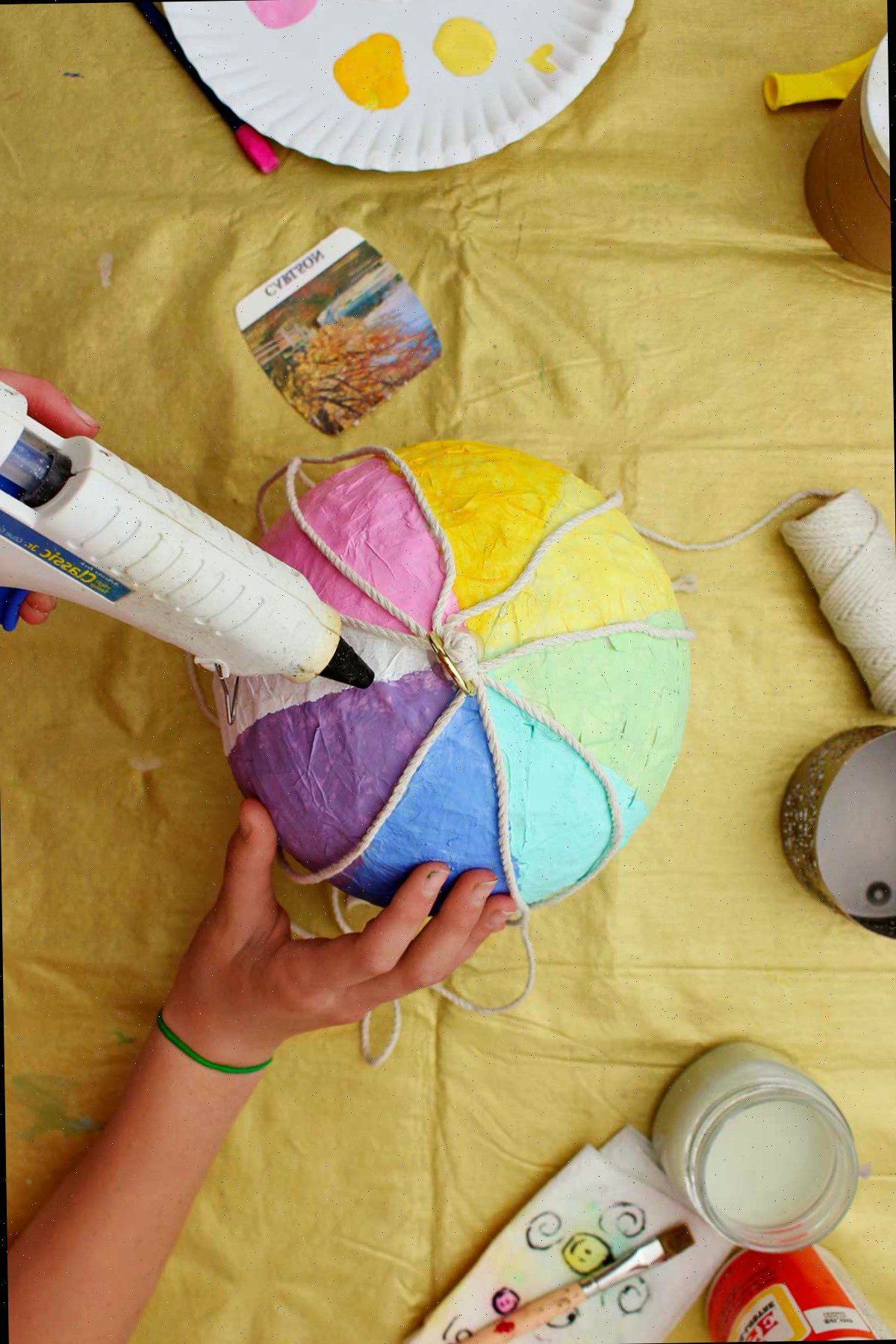 Indivíduo colando seções de corda ao longo das listras pintadas em seu mini balão de ar quente.