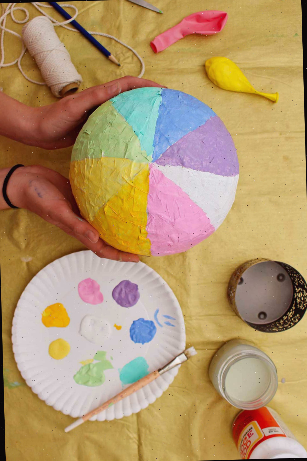 Indivíduo exibindo um balão de ar quente pintado com listras de arco-íris pastel.