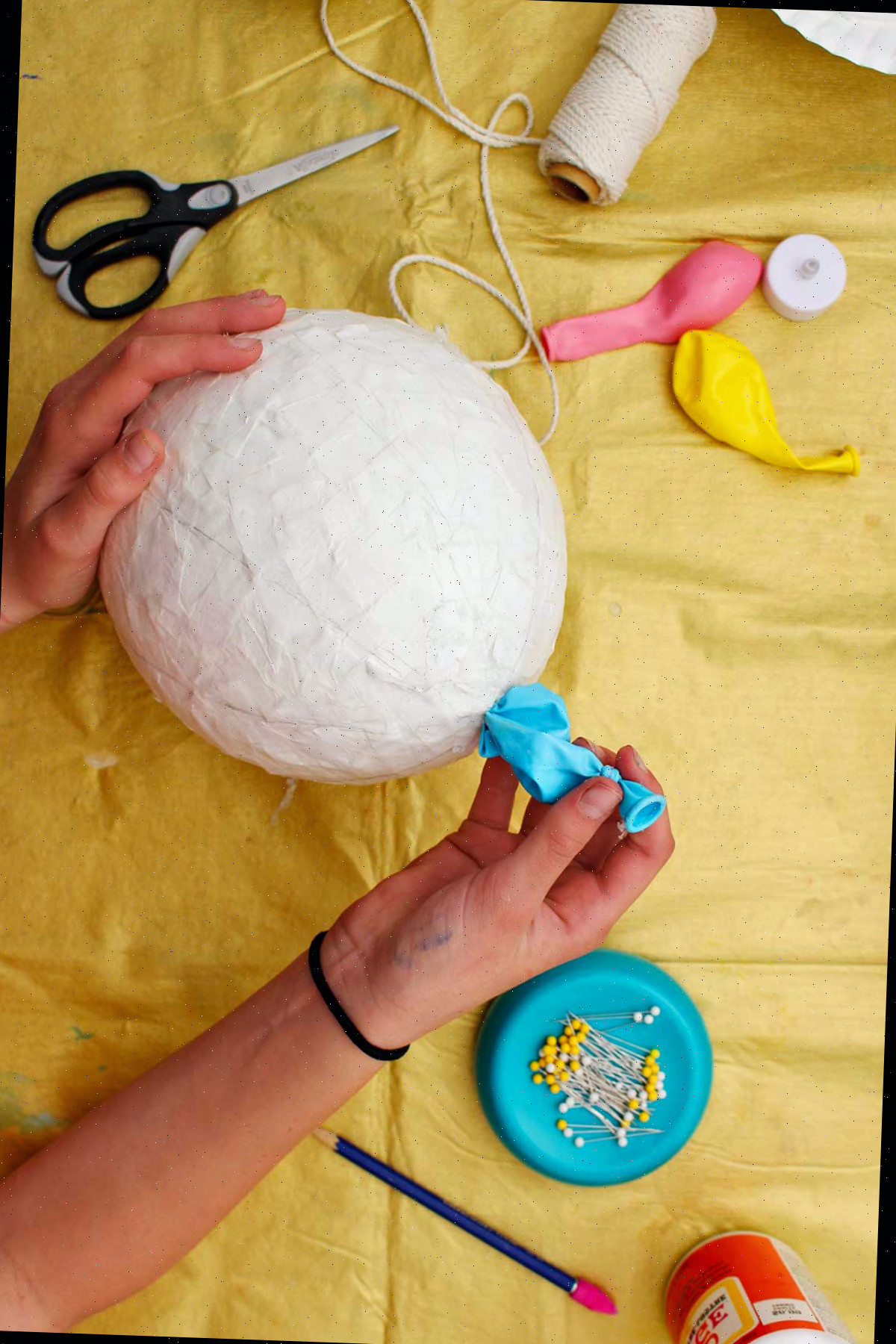 Indivíduo retirando o balão estourado do final de um balão de papel machê seco.