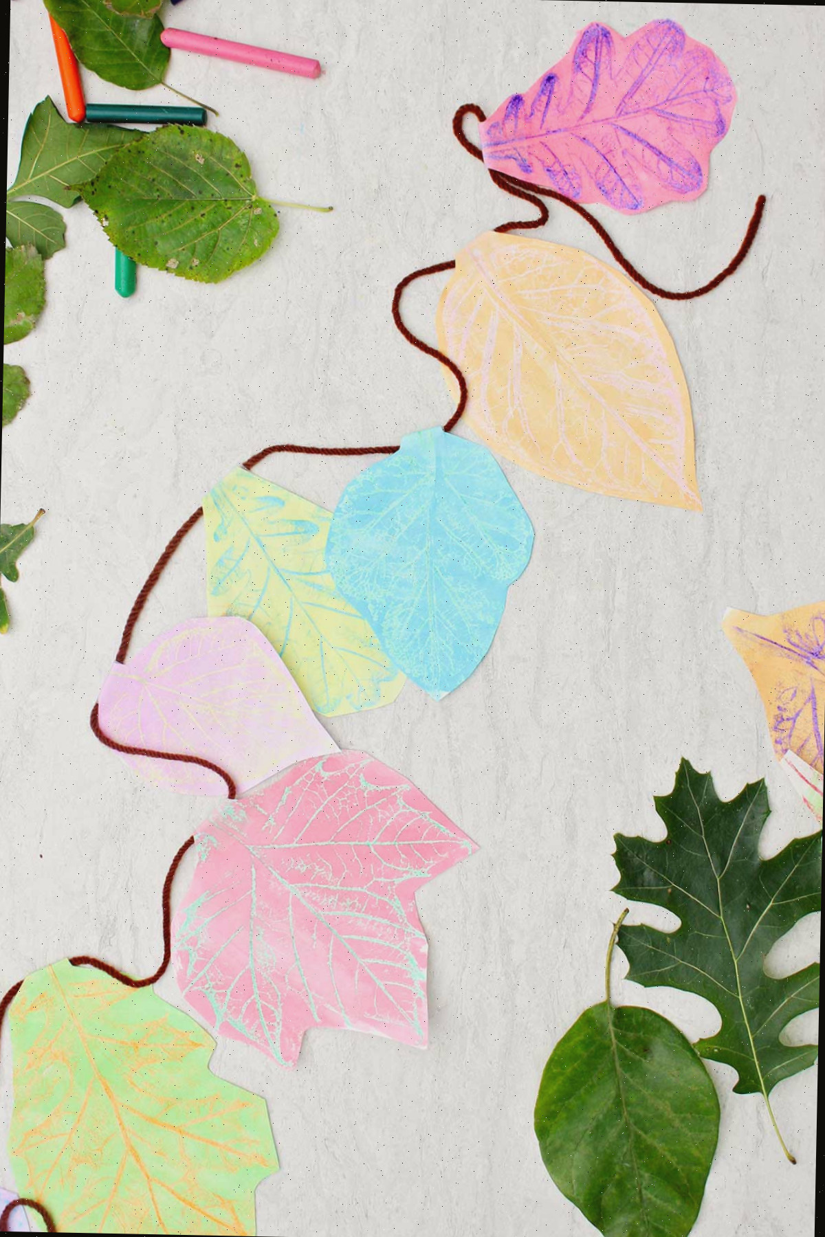 Uma guirlanda de impressões de folhas criadas com várias cores de giz de cera e aquarela.