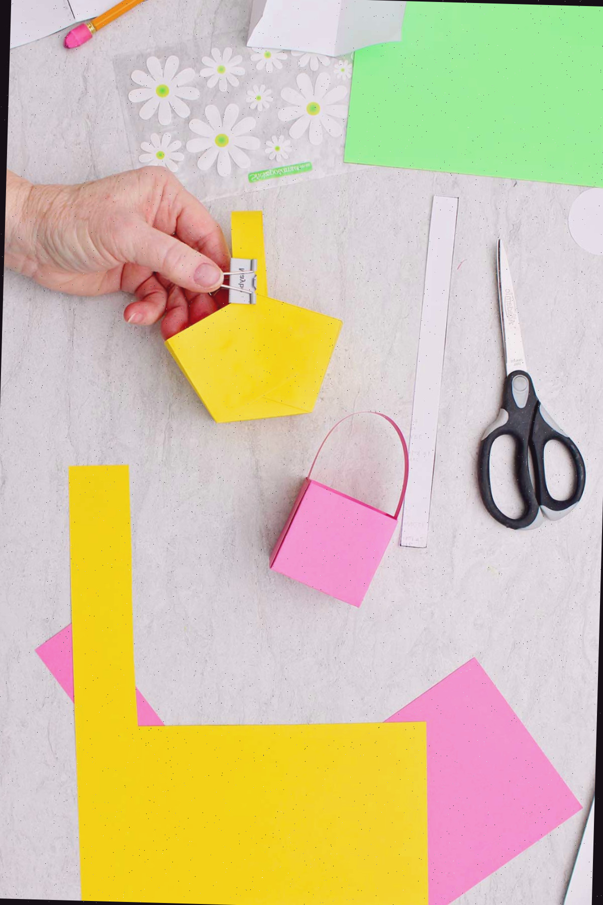 Indivíduo usando um mini clipe de papel na extremidade do cabo para manter a posição correta no mini cesto de Páscoa enquanto seca.