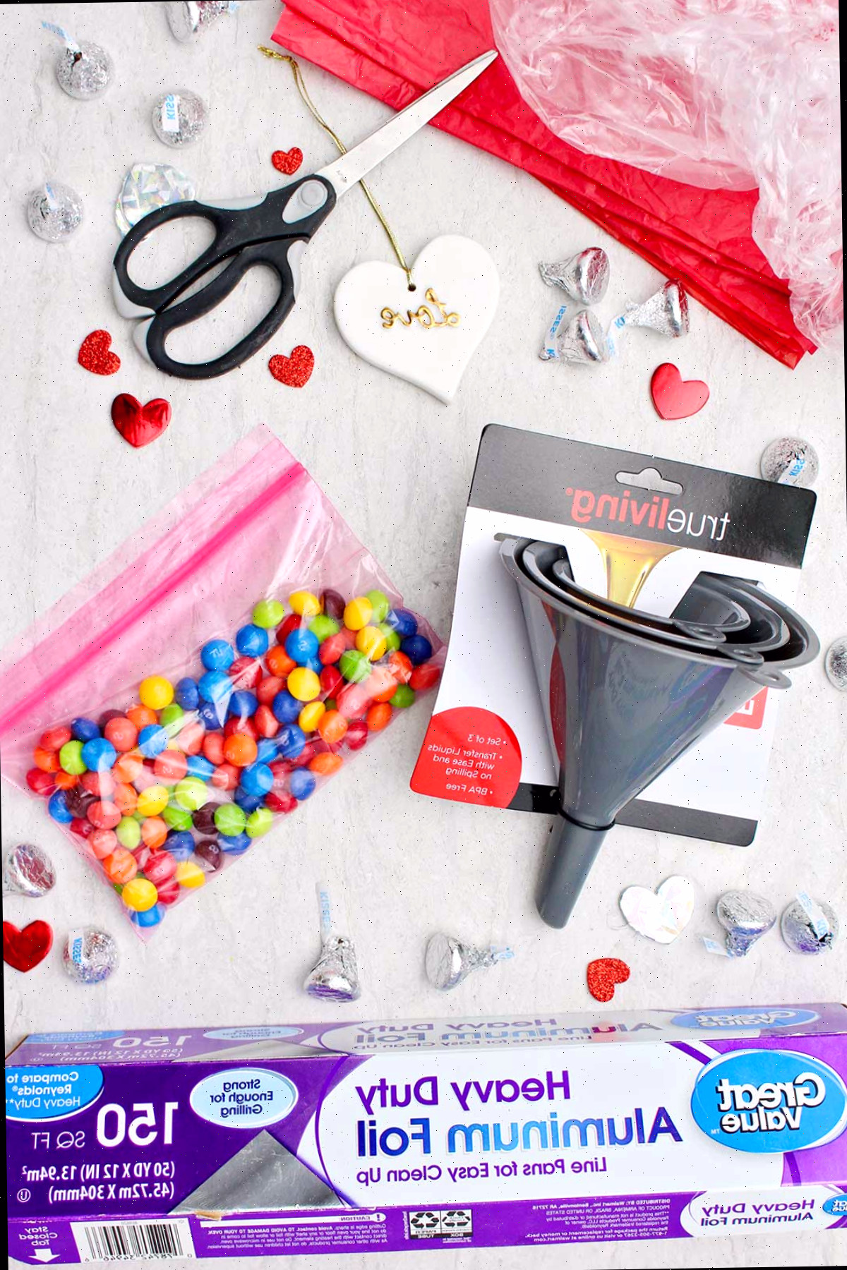 Materiais para criar um gigante Beijo Hershey DIY para o Dia dos Namorados. Funis plásticos, saco de doces, tesoura, papel alumínio e outros pequenos Beijos Hershey.