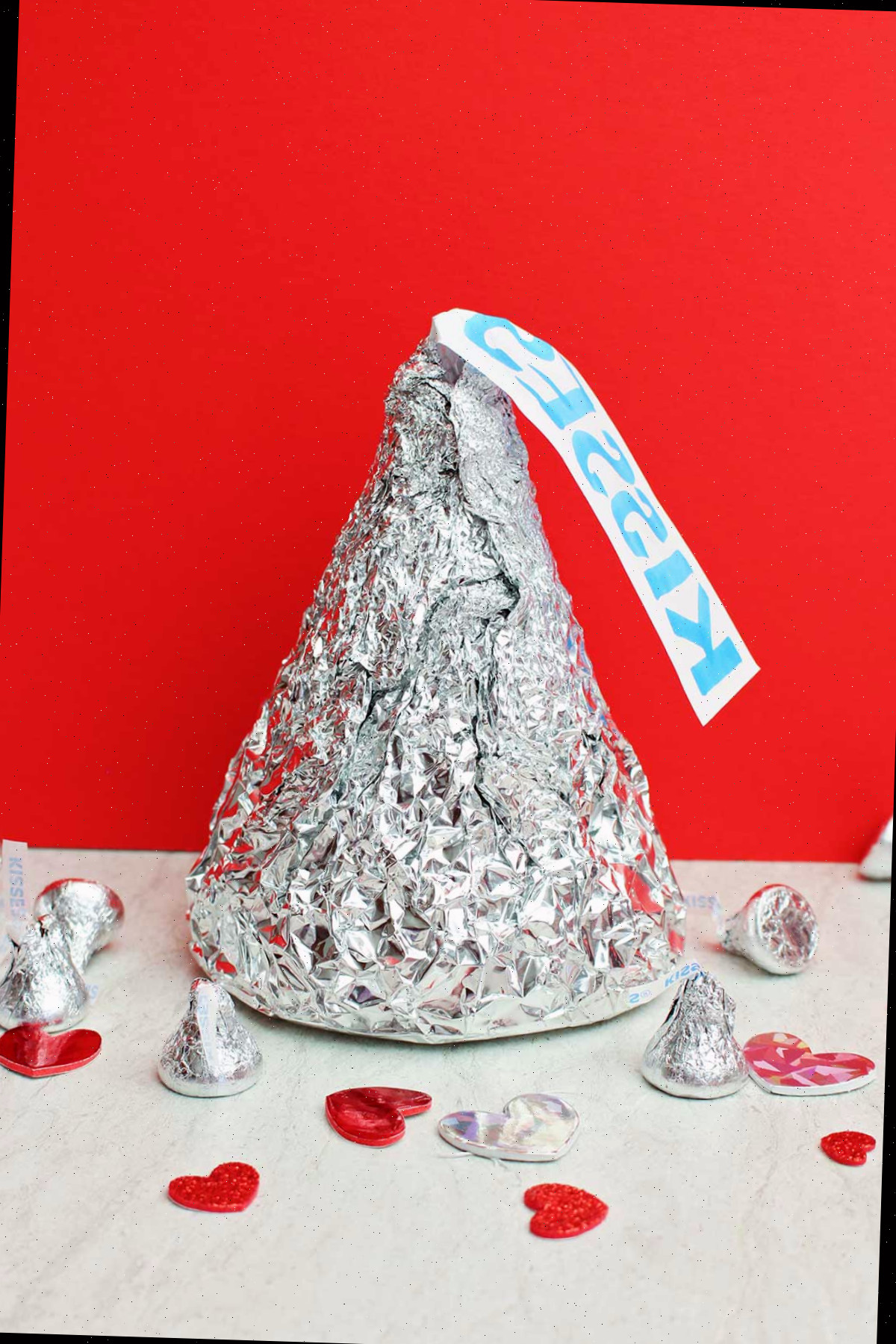 Beijo Gigante de Hershey com beijos em tamanho real e decorações de coração sobre um fundo vermelho.