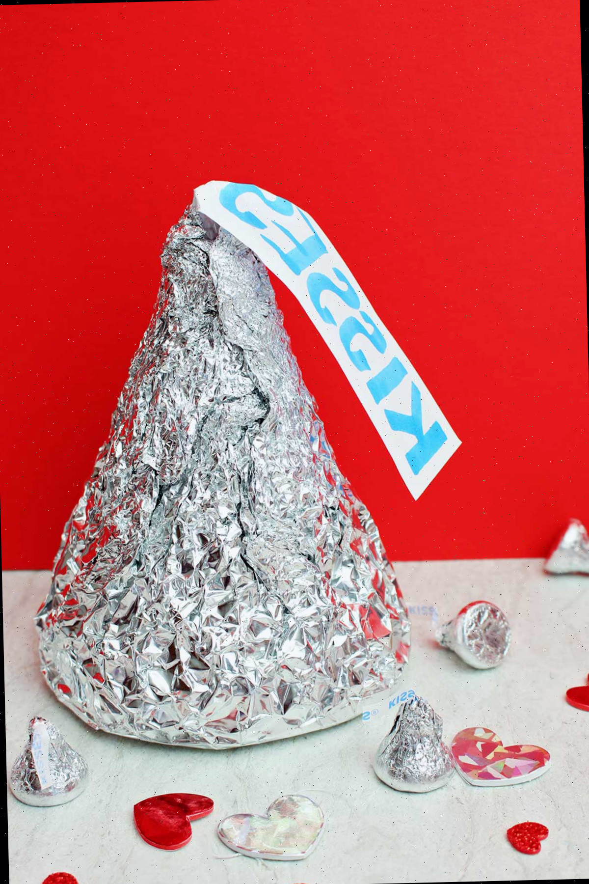 Gigante Beijo Hershey com beijos de tamanho real e decorações de coração contra um fundo vermelho.