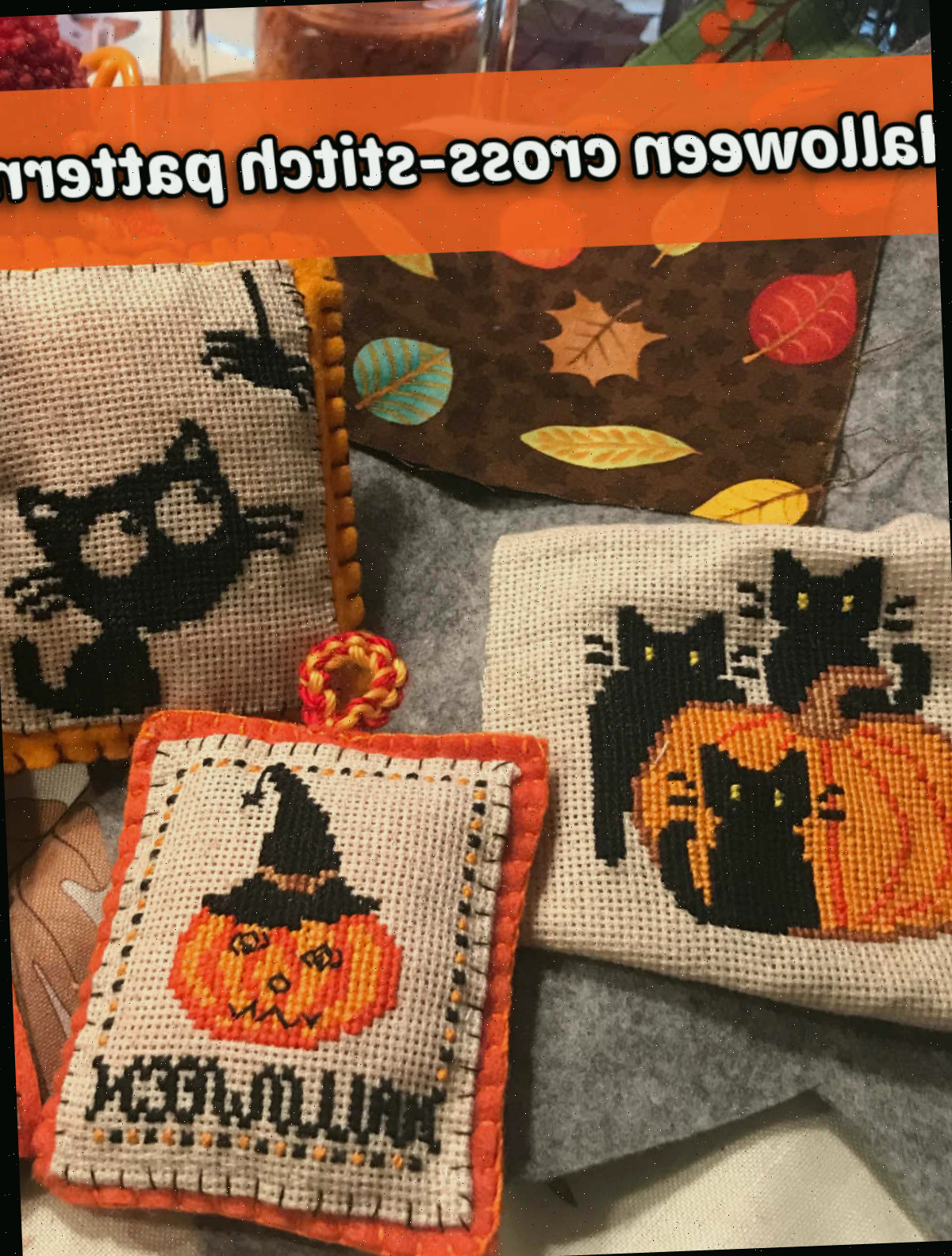 Almofadas, almofadas e tecidos com designs de Halloween. Texto laranja diz padrões de ponto cruz de Halloween.