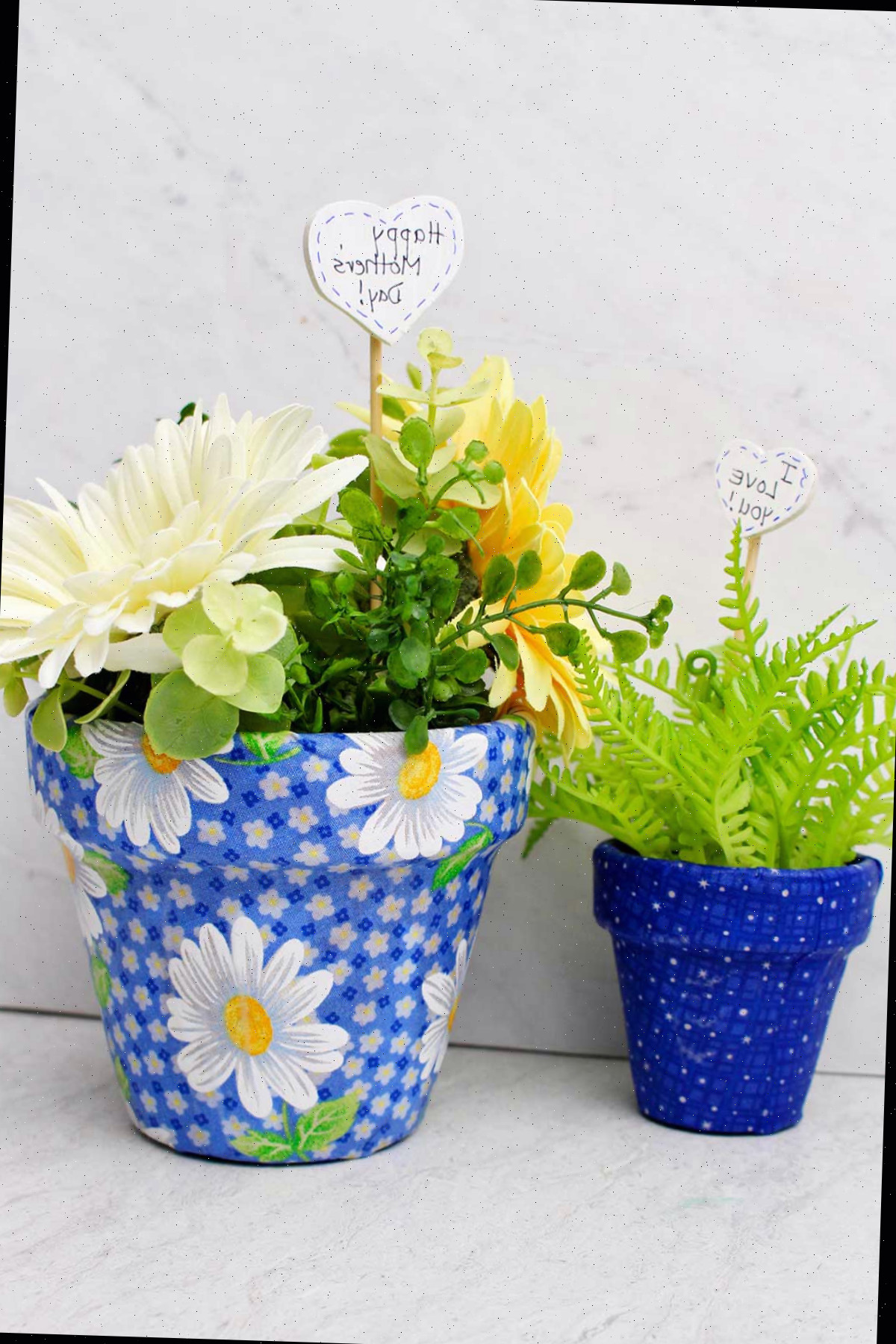 Vasos de flores decoupados com tecido preenchidos com flores de primavera e folhagens.