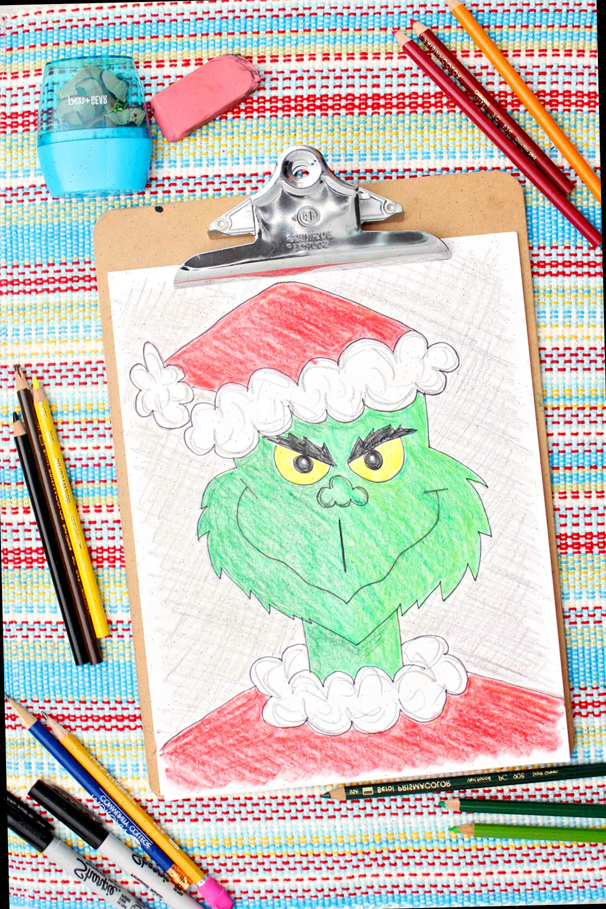 Versão colorida de um esboço do Grinch com lápis coloridos ao lado.