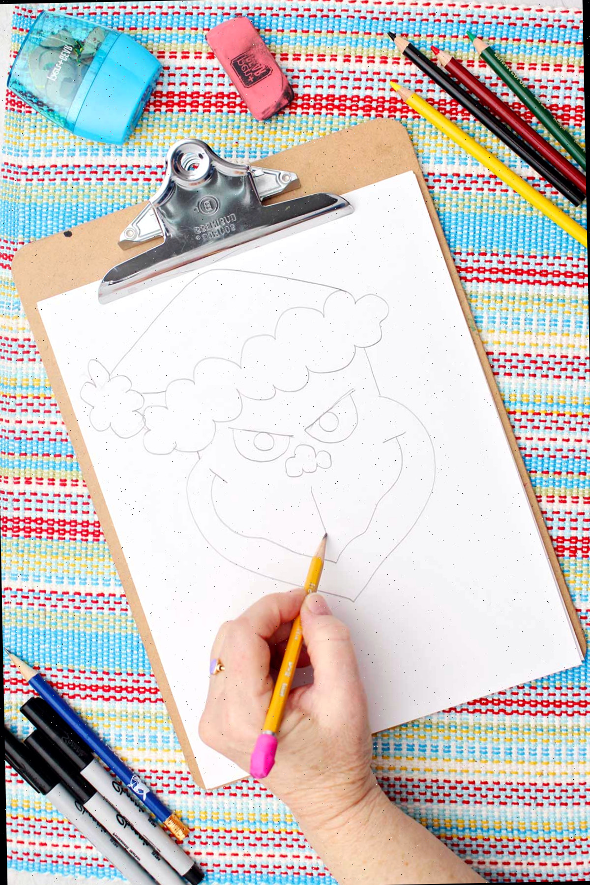 Indivíduo fazendo alguns detalhes faciais no rascunho do Grinch.