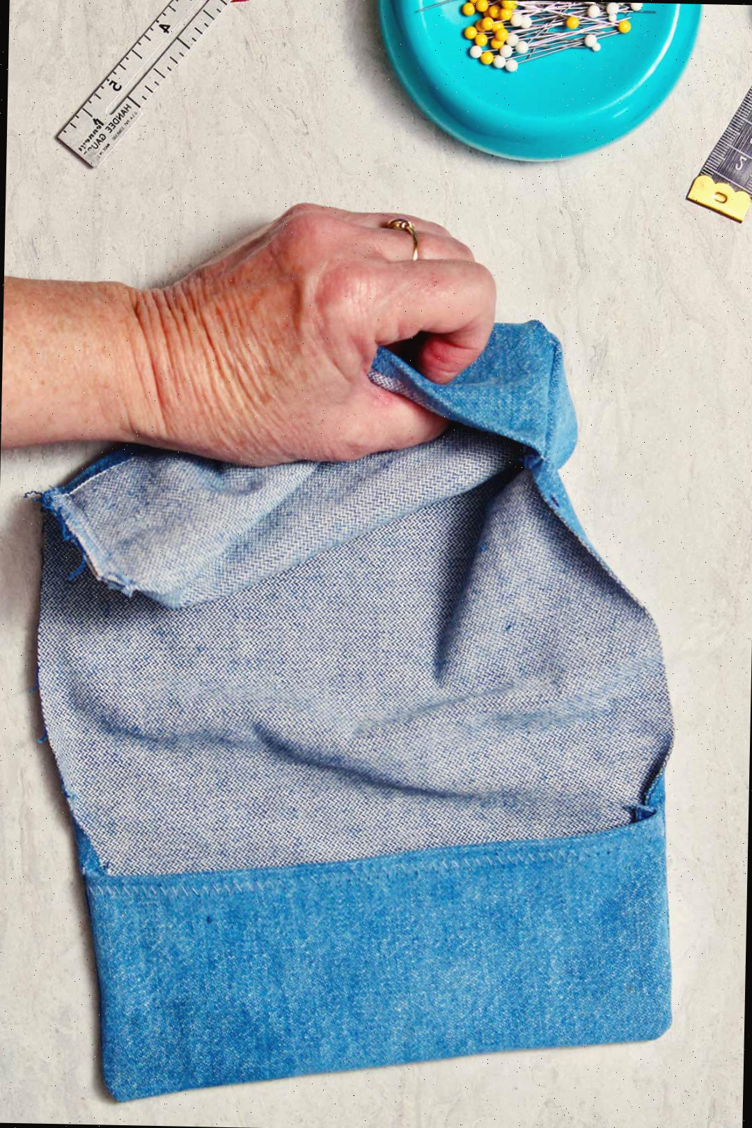 Uma mão virando o tecido de denim para o lado interno.