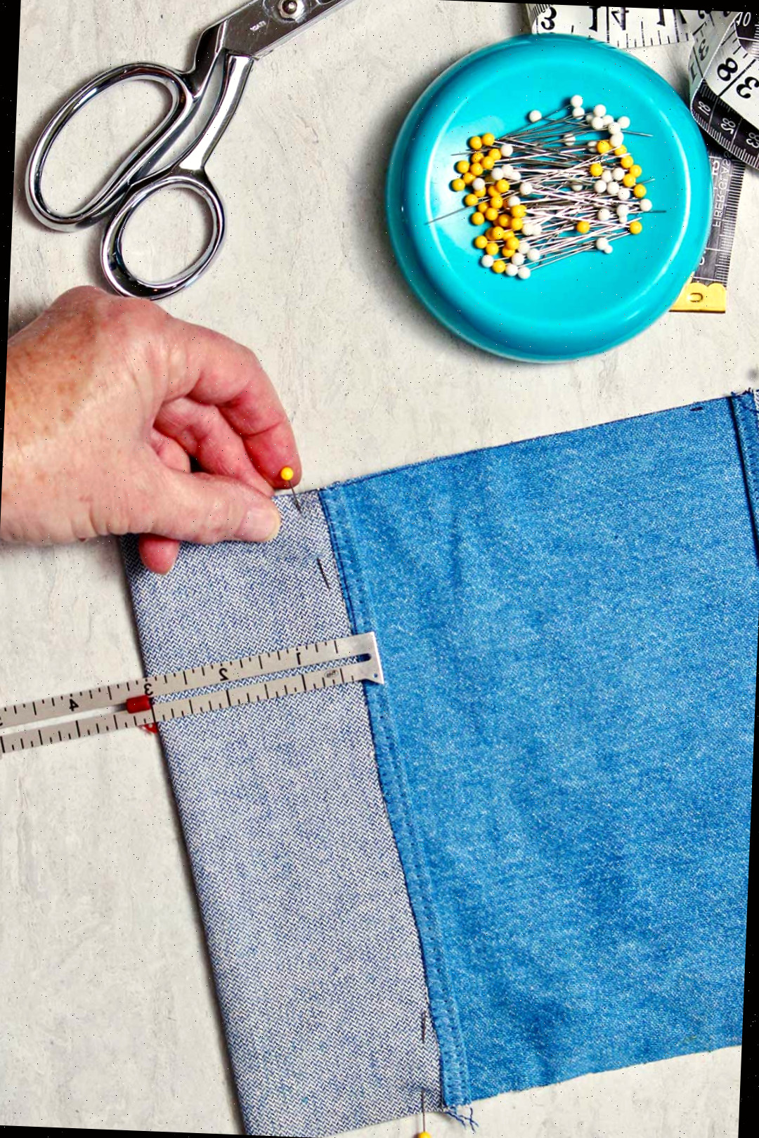Uma pequena régua mede três polegadas no tecido jeans e é fixada para criar uma aba para a capa.