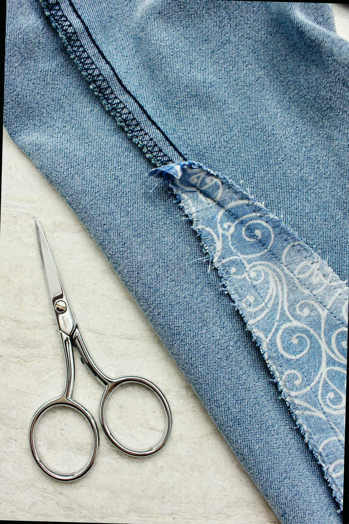 Fechamento da parte interna do jeans do avesso com o pedaço de tecido costurado.