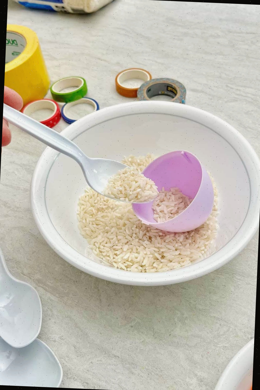 Pessoa preenchendo um ovo de plástico roxo com arroz.