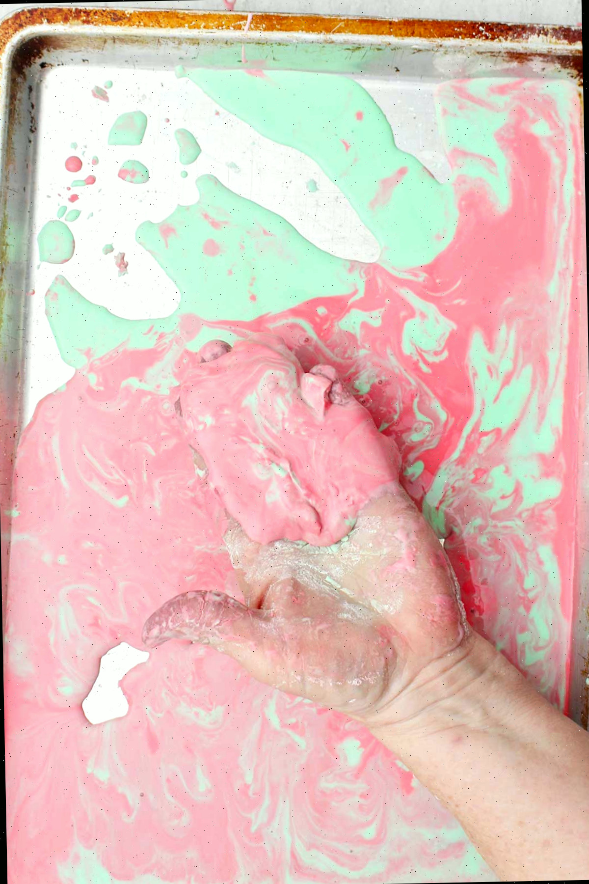 Uma pessoa brincando com uma versão mais líquida do oobleck em uma assadeira.