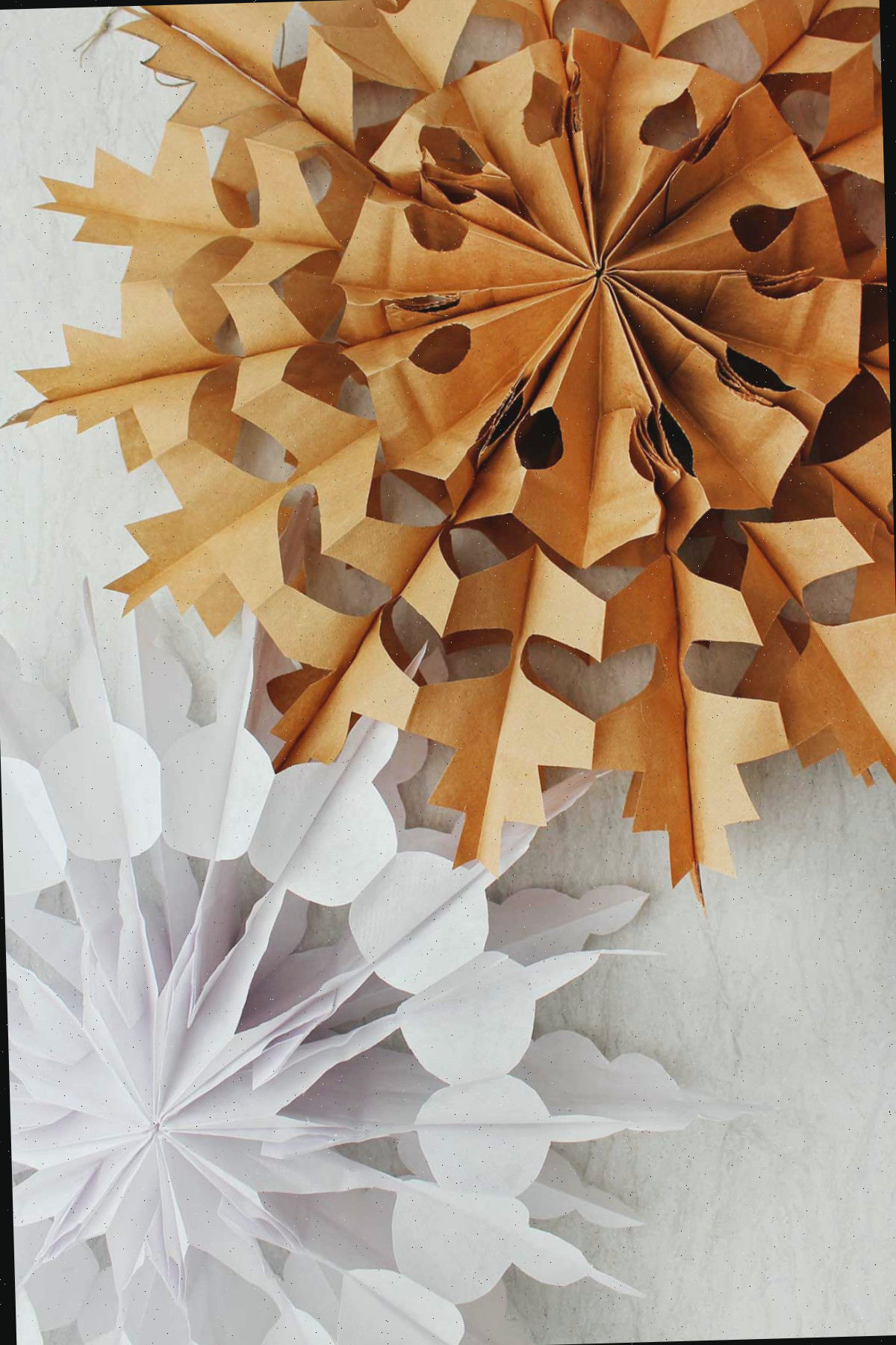 Dois flocos de neve de papel finais. Um em marrom e outro em branco.